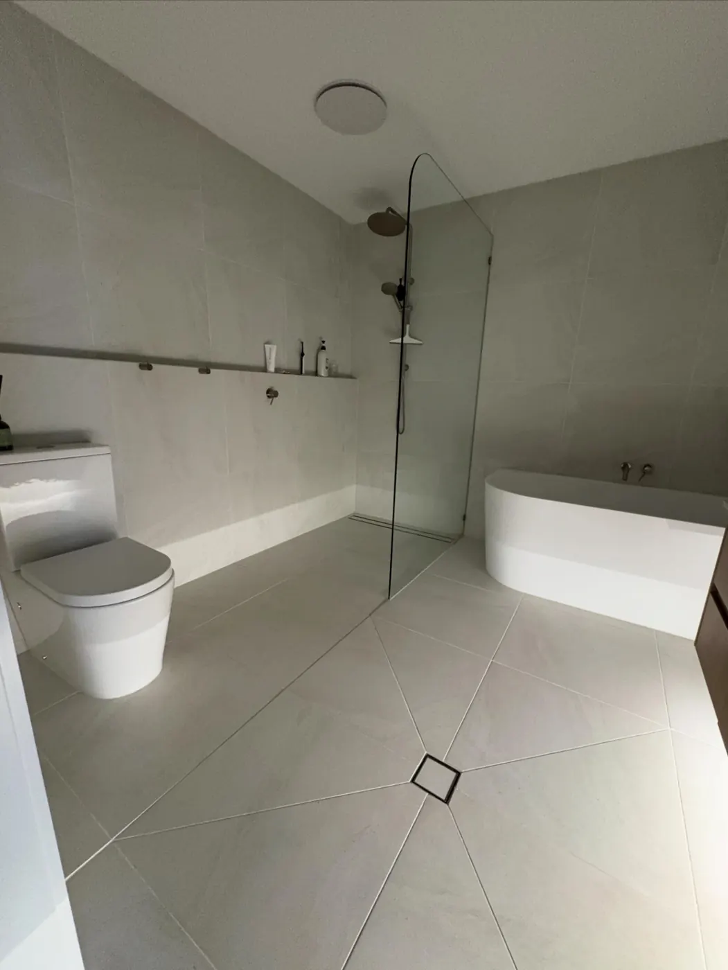 Completed bathroom renovation with frameless walk-in shower, freestanding bath and large-format floor tiles