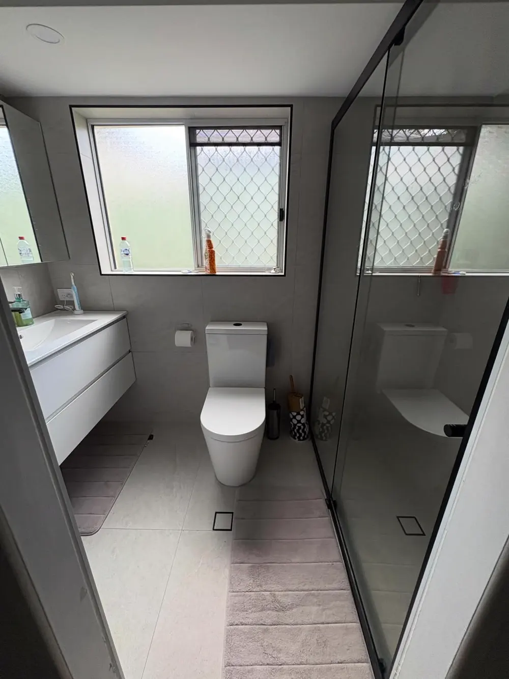 Finished bathroom renovation with large-format stone-look tiles, wall-hung vanity and black-framed shower screen