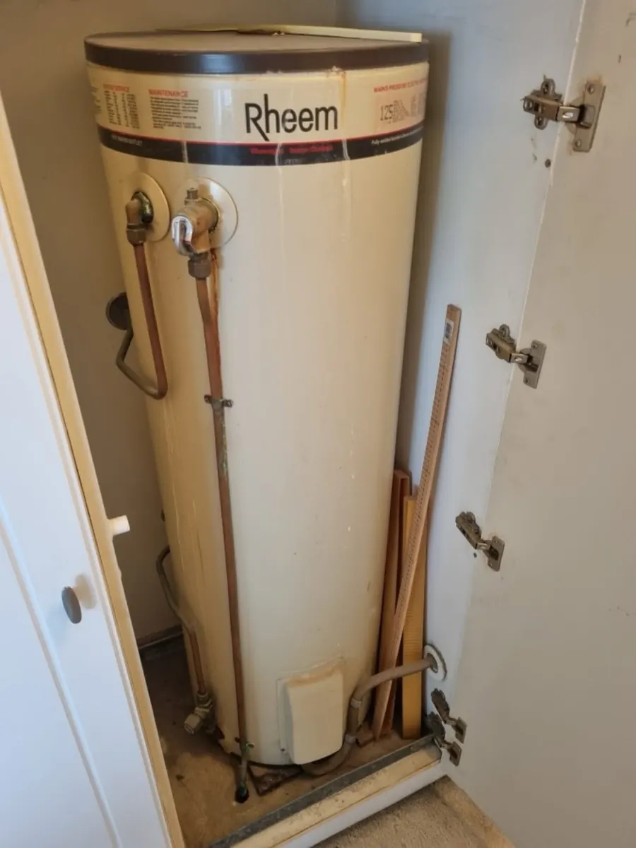 Old corroded Rheem electric hot water system in a cupboard before replacement