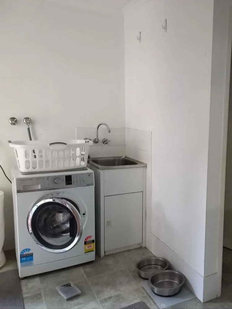Original laundry before renovation with old tub, exposed taps and tiled floor