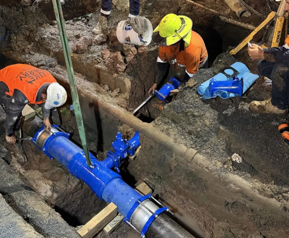 LB Plumbing Group crew installing a blue mains water main and valve in an excavated trench on a civil works site