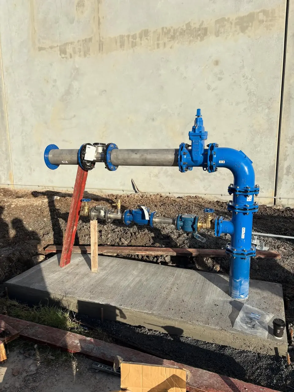 Completed double-stacked water meter set-up on a new concrete slab with blue ductile riser and isolation valves